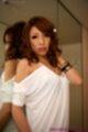 Leaning back against mirror wearing white dress pushing hair back