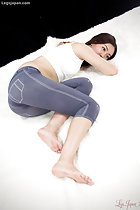 Yukishiro Madoka curled up on her side arm raised in white top wearing pantyhose legs raised her feet bare