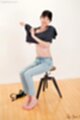 Matsuda anna sitting on stool removing top wearing jeans bare feet pressed together