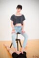 Sitting on stool wearing jeans hands on her thighs hard cock between her bare feet