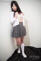 Leaning against wall removing shirt in short skirt