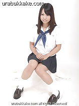 Kogal seated in uniform long hair down over her shoulders hands together on her lap knees pressed together