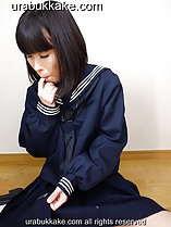 Seated on wooden floor in seifuku uniform sucking her finger